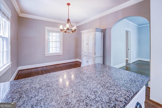 dining area featuring arched walkways, crown molding, dark wood-style flooring, and baseboards