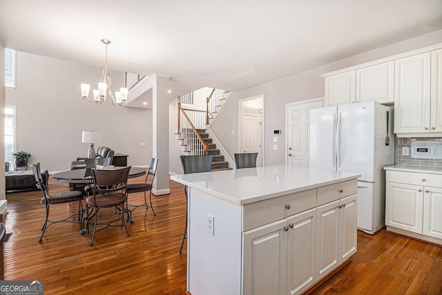 kitchen with a kitchen island, wood finished floors, white cabinets, backsplash, and freestanding refrigerator