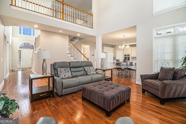 living area featuring stairway, dark wood-style flooring, plenty of natural light, and a notable chandelier