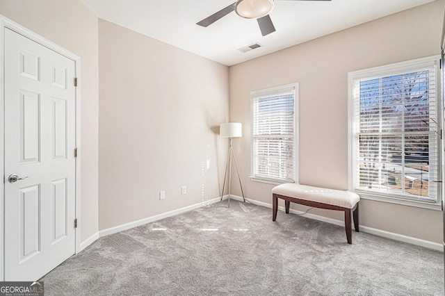 living area with baseboards, visible vents, ceiling fan, and carpet flooring