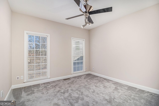 carpeted empty room featuring visible vents, a ceiling fan, and baseboards