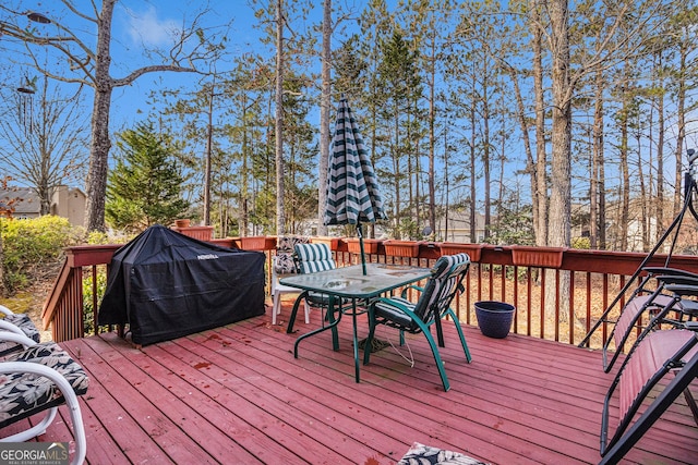 wooden deck with outdoor dining area and area for grilling