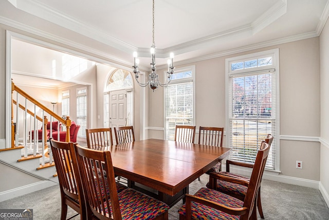 carpeted dining area featuring a tray ceiling, crown molding, stairway, a chandelier, and baseboards