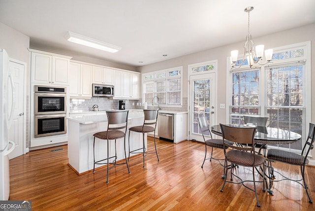 kitchen featuring appliances with stainless steel finishes, light wood-type flooring, and backsplash