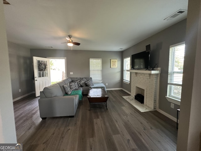 living room with dark wood-style flooring, a fireplace, visible vents, and baseboards