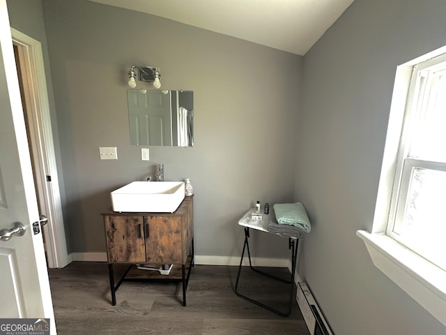 bathroom with baseboards, vaulted ceiling, wood finished floors, and vanity