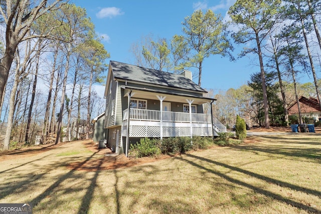 view of front facade featuring covered porch, driveway, a chimney, and a front yard