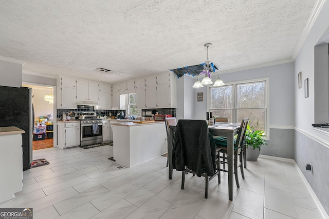 kitchen with pendant lighting, crown molding, stainless steel appliances, light countertops, and backsplash