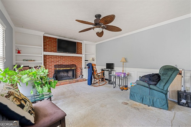 carpeted living area with a wainscoted wall, built in shelves, a brick fireplace, and crown molding