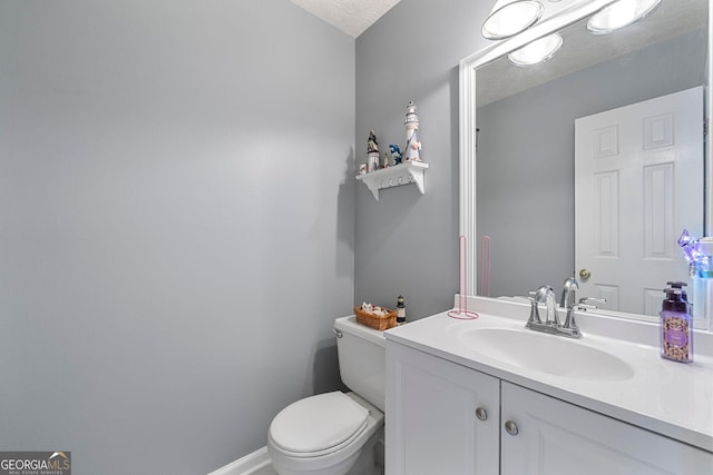 half bath featuring a textured ceiling, vanity, toilet, and baseboards