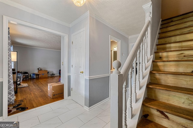 stairs featuring a textured ceiling, marble finish floor, and ornamental molding