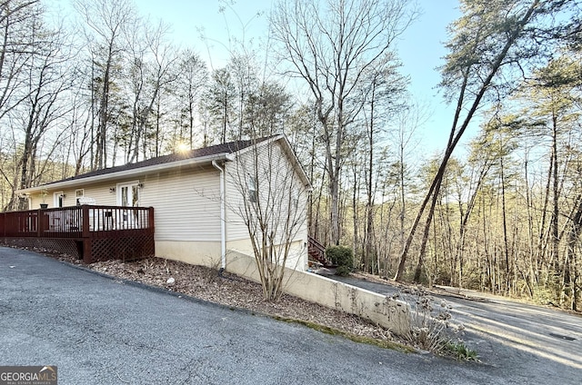 view of side of property featuring driveway, a deck, and an attached garage