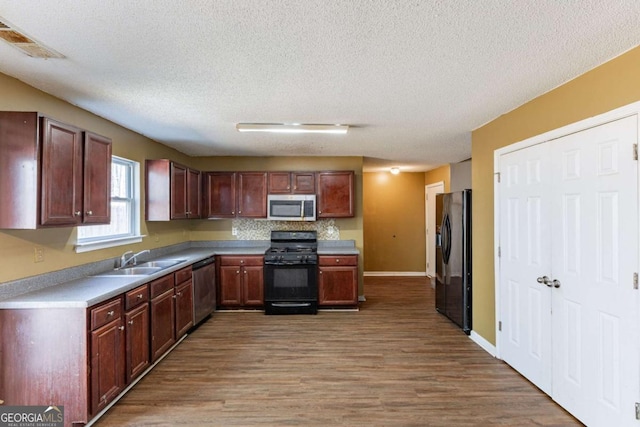 kitchen with visible vents, wood finished floors, light countertops, black appliances, and a sink