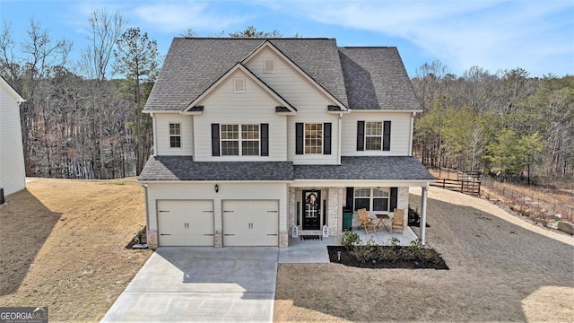 traditional-style house with a garage, covered porch, roof with shingles, and concrete driveway