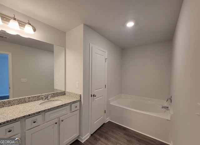 full bath with a bath, wood finished floors, and vanity