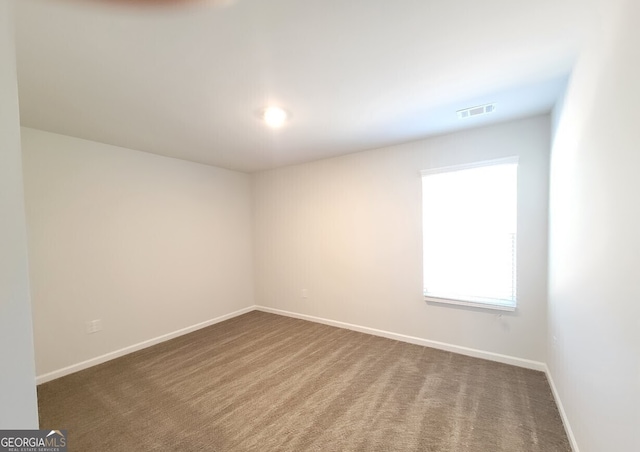 empty room featuring baseboards, visible vents, and carpet flooring