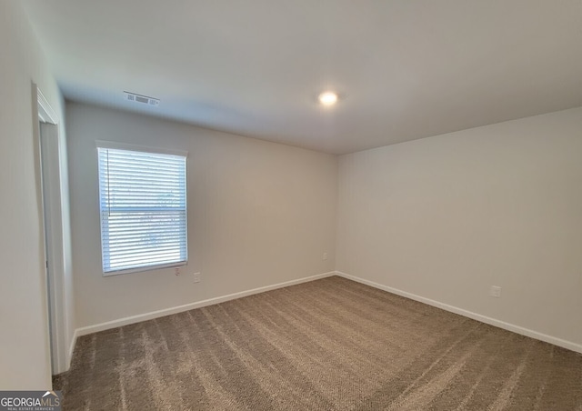 empty room featuring carpet, visible vents, and baseboards