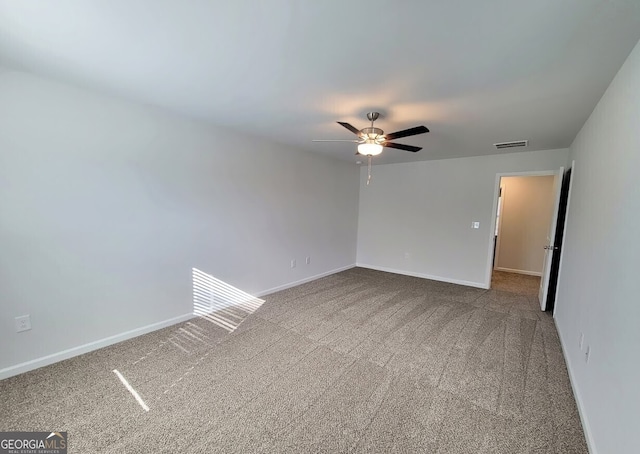 empty room with carpet floors, visible vents, ceiling fan, and baseboards