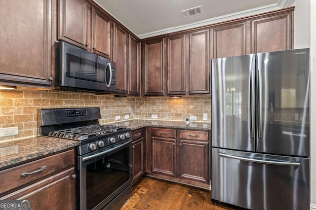 kitchen with stainless steel appliances, dark wood-style floors, visible vents, decorative backsplash, and dark stone counters