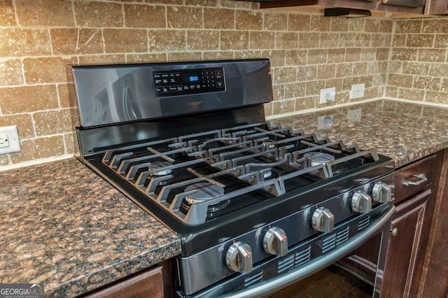 details featuring dark stone counters, dark brown cabinetry, backsplash, and black range with gas stovetop