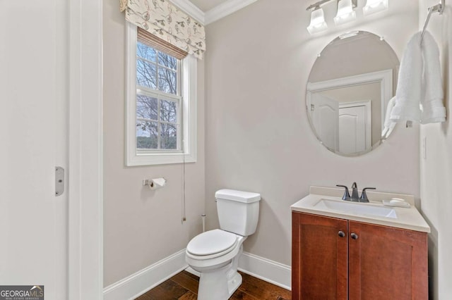 half bathroom with toilet, ornamental molding, vanity, wood finished floors, and baseboards