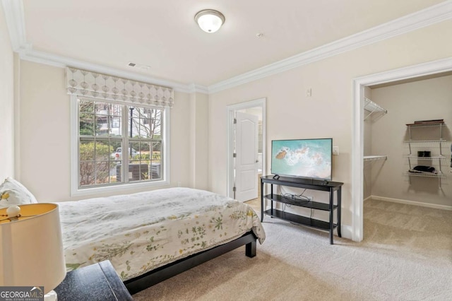 carpeted bedroom featuring ornamental molding, a walk in closet, visible vents, and baseboards