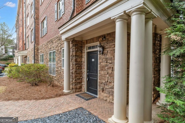 entrance to property featuring stone siding and brick siding