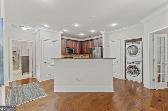 kitchen featuring stainless steel appliances, stacked washer / dryer, dark wood finished floors, and ornamental molding