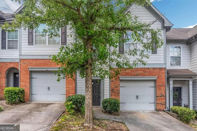 multi unit property with a garage, concrete driveway, and brick siding