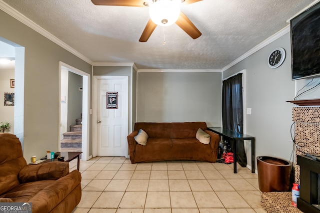 living area featuring light tile patterned floors, ceiling fan, stairway, and a textured ceiling