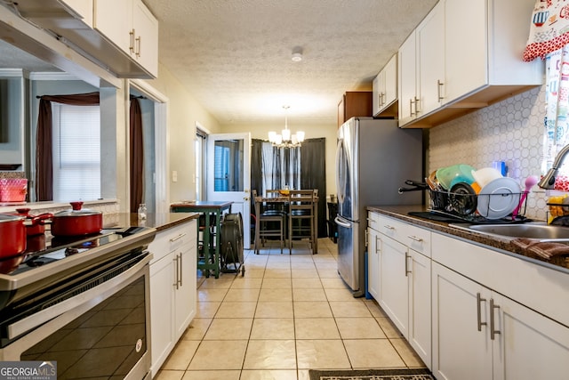 kitchen with dark countertops, light tile patterned floors, white cabinets, and stainless steel appliances