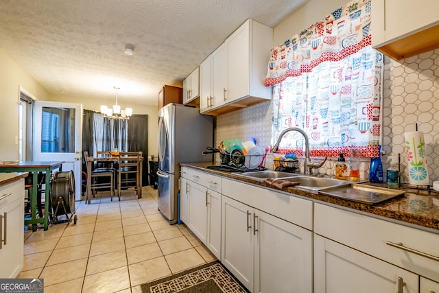 kitchen with dark countertops, freestanding refrigerator, decorative backsplash, and light tile patterned floors