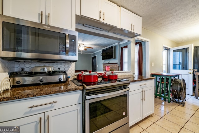 kitchen featuring light tile patterned floors, appliances with stainless steel finishes, white cabinets, and decorative backsplash