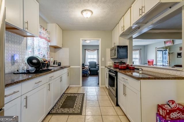 kitchen featuring appliances with stainless steel finishes, white cabinetry, decorative backsplash, and light tile patterned floors