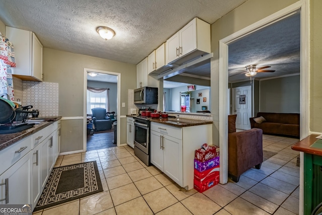 kitchen featuring light tile patterned floors, white cabinetry, appliances with stainless steel finishes, and backsplash