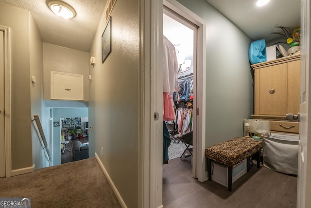 hallway with a textured ceiling, an upstairs landing, and baseboards