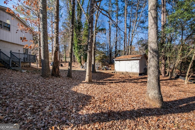 view of yard with an outbuilding, a storage unit, stairs, and a deck