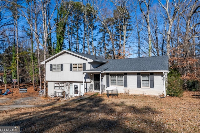 tri-level home featuring brick siding and roof with shingles