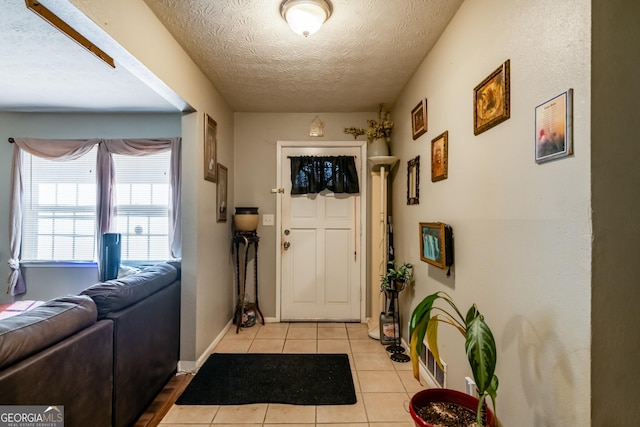 foyer entrance with baseboards, a textured ceiling, and light tile patterned flooring