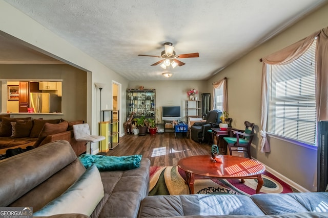 living room with baseboards, a textured ceiling, a ceiling fan, and wood finished floors