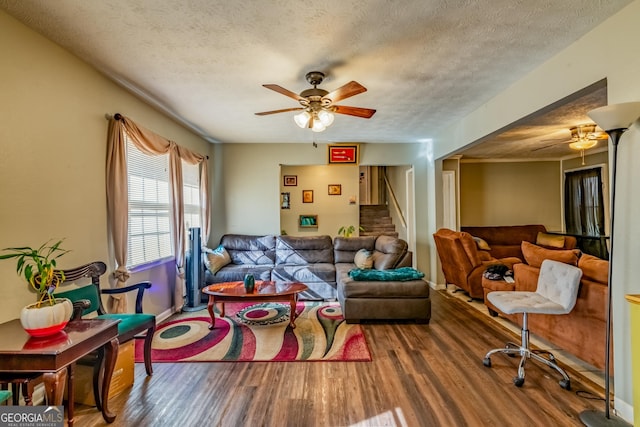 living room featuring stairs, a textured ceiling, wood finished floors, and a ceiling fan