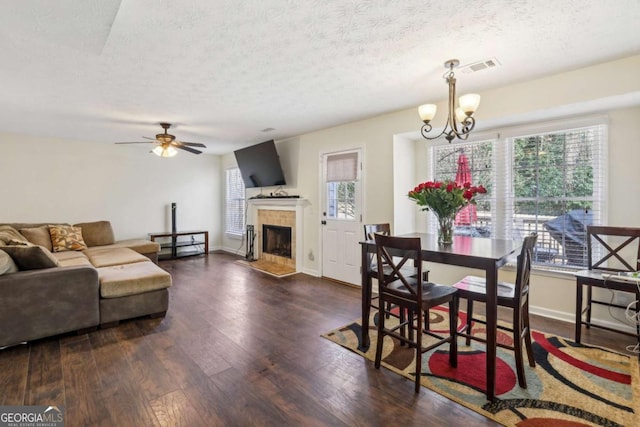 dining area featuring wood-type flooring, a tile fireplace, visible vents, and baseboards