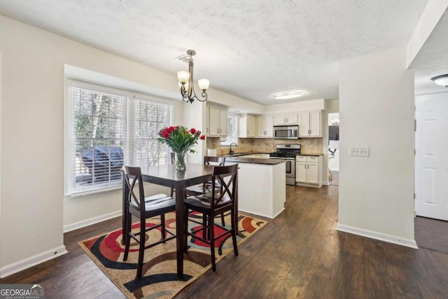 dining room featuring dark wood-style floors, baseboards, a textured ceiling, and an inviting chandelier