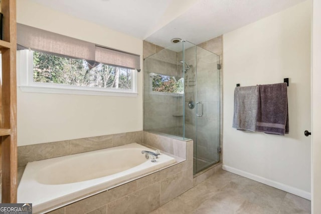 bathroom with a shower stall, baseboards, and a bath