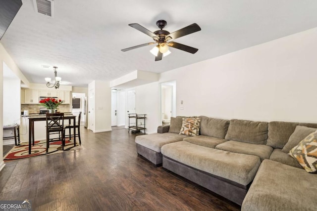 living area featuring dark wood-style floors, baseboards, visible vents, and ceiling fan with notable chandelier