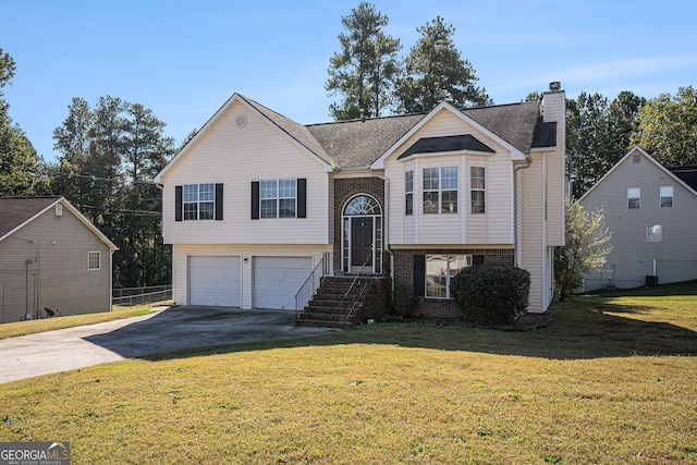 split foyer home featuring brick siding, a chimney, concrete driveway, an attached garage, and a front yard