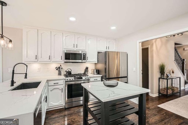 kitchen featuring light stone countertops, appliances with stainless steel finishes, white cabinets, and a sink