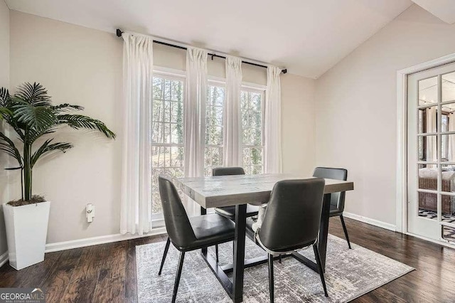 dining space with dark wood-type flooring, lofted ceiling, and baseboards