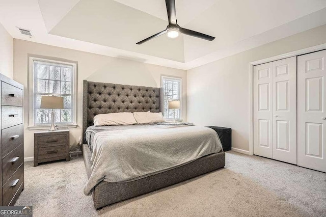 bedroom with carpet floors, a tray ceiling, a closet, and visible vents