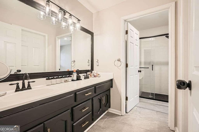 full bathroom with double vanity, a stall shower, a sink, and baseboards